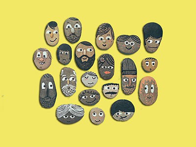 a group of 20 pebbles decorated with facial features and hair, of people of different ethnic backgrounds and different expressions, on a yellow background
